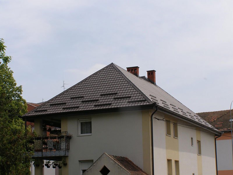 Višespratna kuća sa tamnim krovom od lima u obliku crepa i olucima